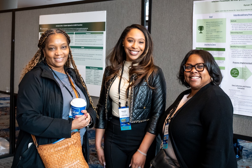 conference attendees smiling in front of posters